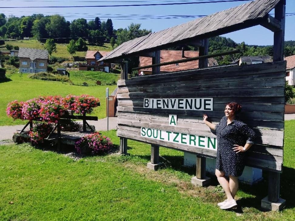 SoultzerenにあるRésidence SoAnSa du Gérardmer - Col de la Schluchtの水分計手密法を用いた看板の横に立つ女性