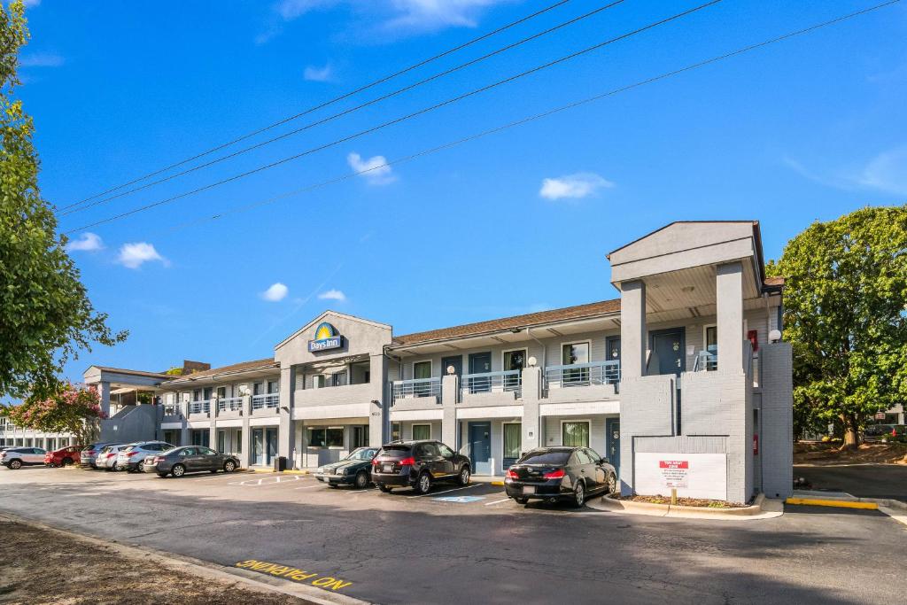 um edifício de escritórios com carros estacionados em frente em Days Inn by Wyndham Raleigh Glenwood-Crabtree em Raleigh