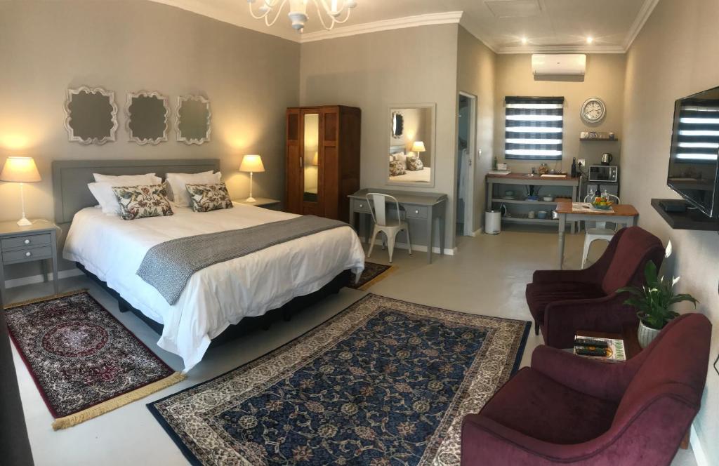 een slaapkamer met een bed en een bank en stoelen bij Steenkoppies estate semi self catering unit 1 in Magaliesburg