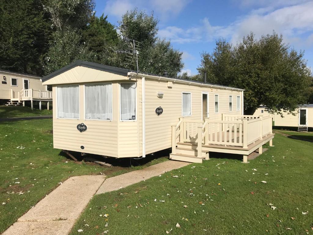 a small white house with a porch in a yard at 3 Bedroom Caravan KG37, Dog Friendly, Shanklin, Isle of Wight in Shanklin