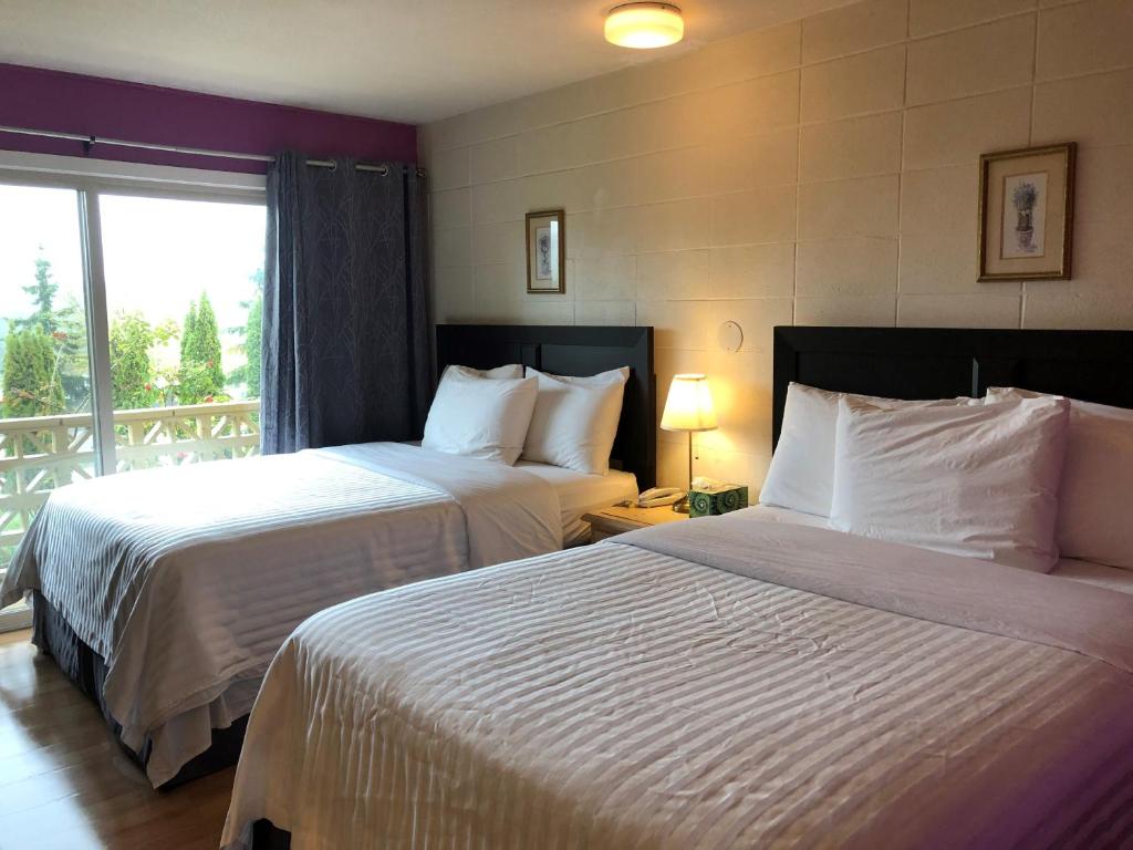 a hotel room with two beds and a balcony at Holiday House Motel in Ladysmith