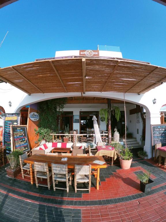 einen Holztisch und Stühle unter einem Holzschirm in der Unterkunft Bamboo Lodge Paracas in Paracas