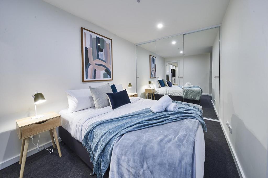 een slaapkamer met een groot bed en een spiegel bij Mega Style Apartments The International in Melbourne