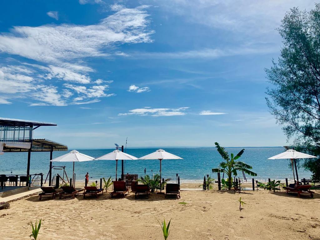 una spiaggia con sedie e ombrelloni e l'oceano di Naroth Beach Bungalow a Koh Rong Island