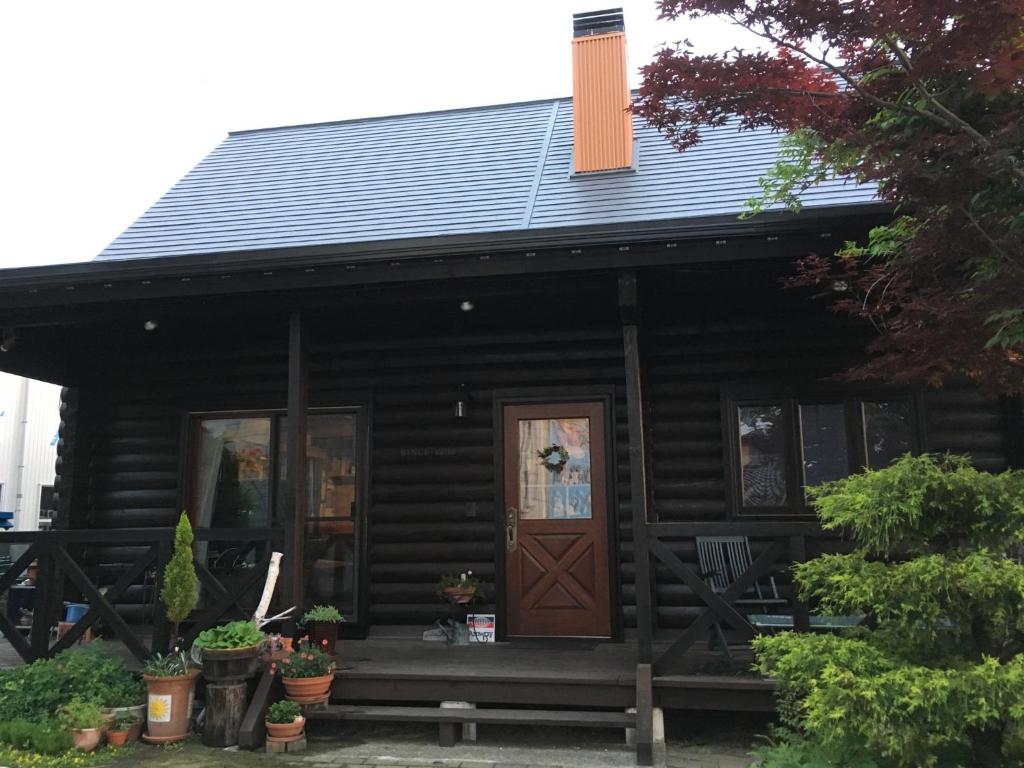 a log cabin with a porch and a door at Carrefour Guesthouse カルフール ゲストハウス in Yokamachi
