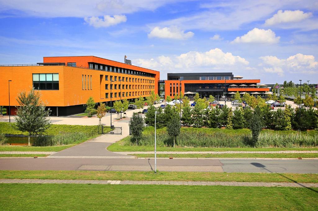 an orange building with a parking lot in front of it at Van Der Valk Hotel Almere in Almere