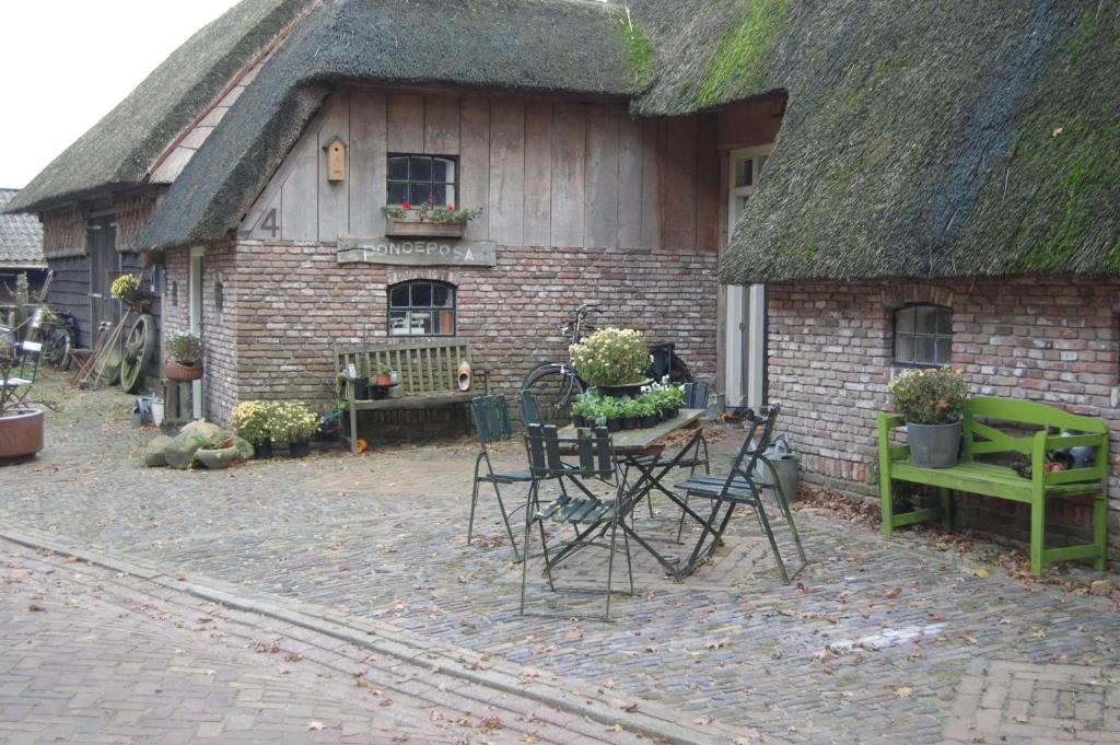 ein Haus mit einem Grasdach mit einem Tisch und Stühlen in der Unterkunft B&B Onze Deel in Hijken