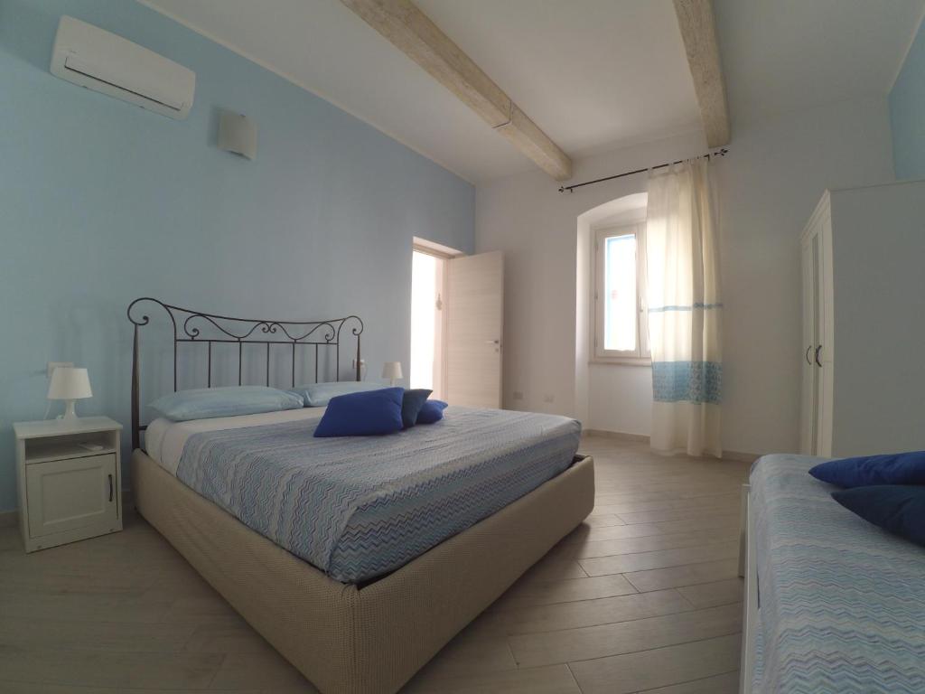 um quarto com uma cama com almofadas azuis e uma janela em Alemar Casa Vacanze em Calasetta