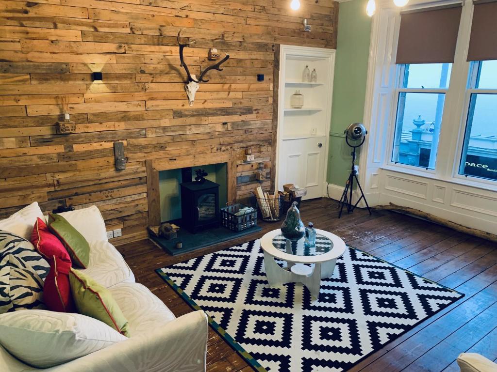 a living room with a wooden wall with a fireplace at Bridge View Apt - stunning River Tay views in Fife