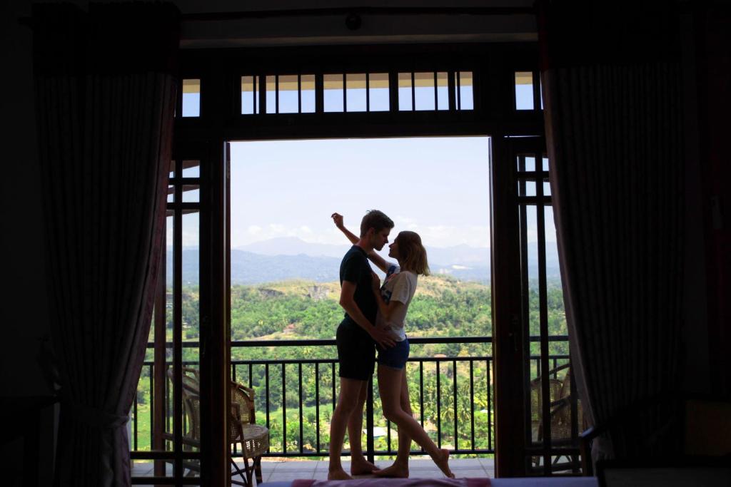 a man and a woman standing in front of a window at Serenity Hill Oasis in Kandy