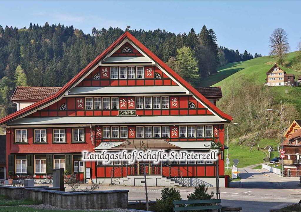 - un grand bâtiment rouge avec un panneau dans l'établissement Landgasthof Schäfle, à Sankt Peterzell