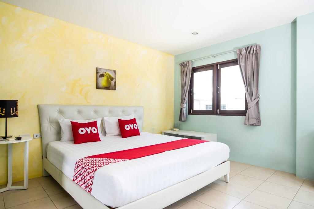 1 dormitorio con 1 cama blanca grande con almohadas rojas en OYO 345 The Click Guesthouse At Chalong, en Rawai Beach
