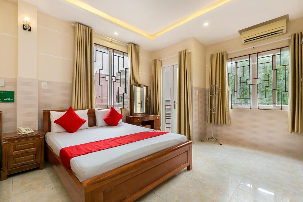 a bedroom with a bed with red pillows and windows at Ngoc Linh Hotel in Ho Chi Minh City