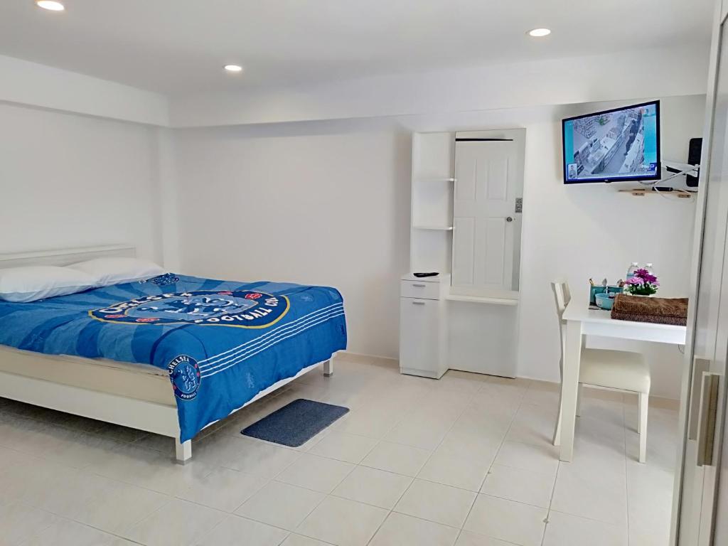 Amy's beach apartments في رايونغ: غرفة نوم بسرير ومكتب وتلفزيون