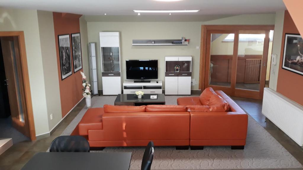 ein Wohnzimmer mit einem orangenen Sofa und einem TV in der Unterkunft Apartmán Lidická in Vracov