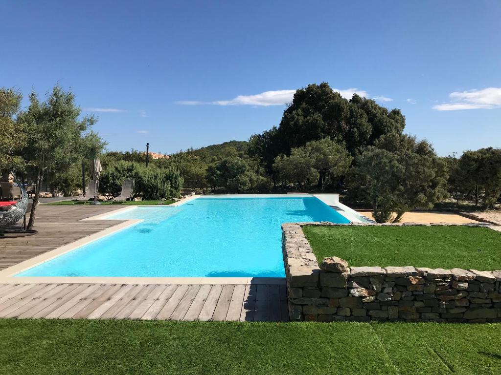 a swimming pool in a yard with a stone wall at Le Domaine du Cade-Gîtes d'exception 4étoiles "La Villa du Cade" in Cazevieille