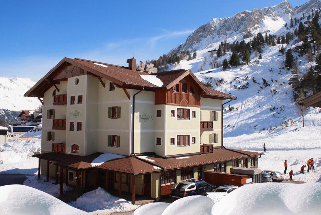 a large building in the snow with a mountain at Hotel Tauernglöckl in Obertauern