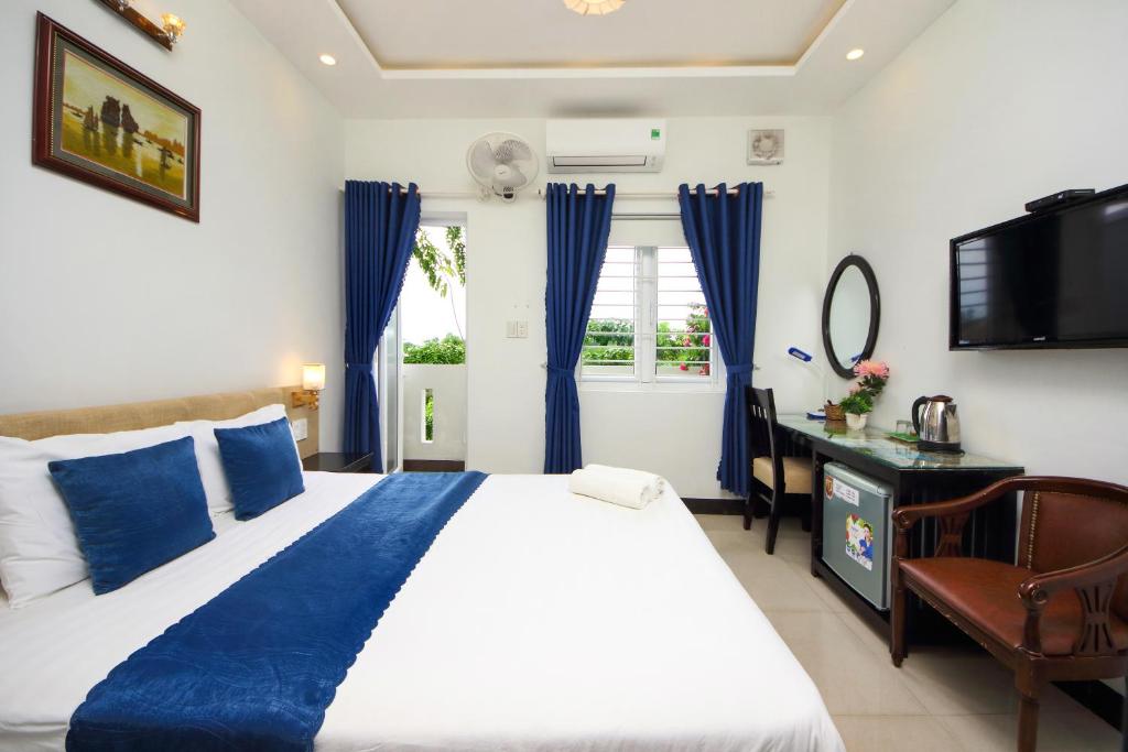 a bedroom with a bed and a desk and a television at Flame Flowers Homestay in Hoi An