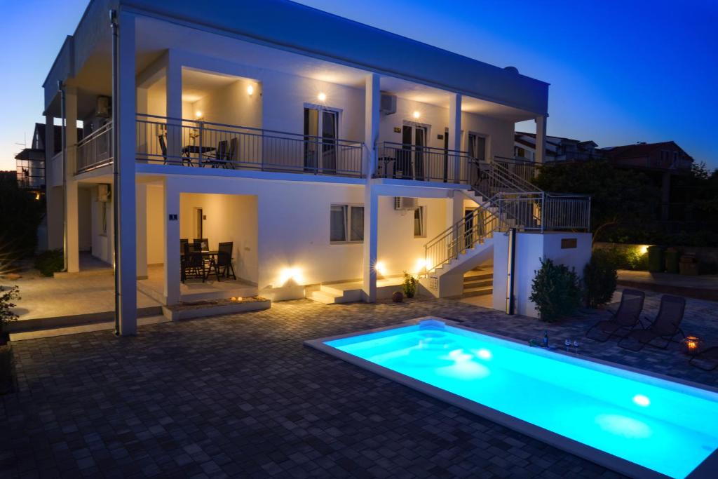 a villa with a swimming pool in front of a house at TayLa-Apartment Vodice in Vodice