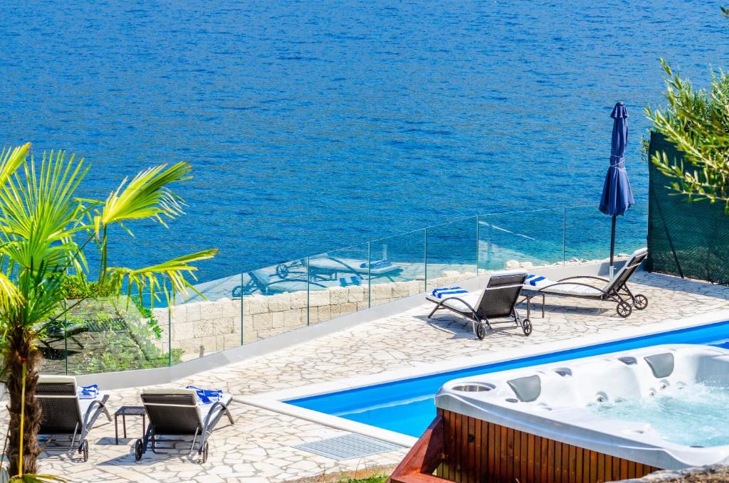 a pool with chairs and a hot tub next to the water at Villa Gabriela in Korčula