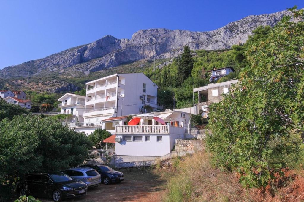 a group of houses and cars parked next to a mountain at Apartments Damjan in Brist