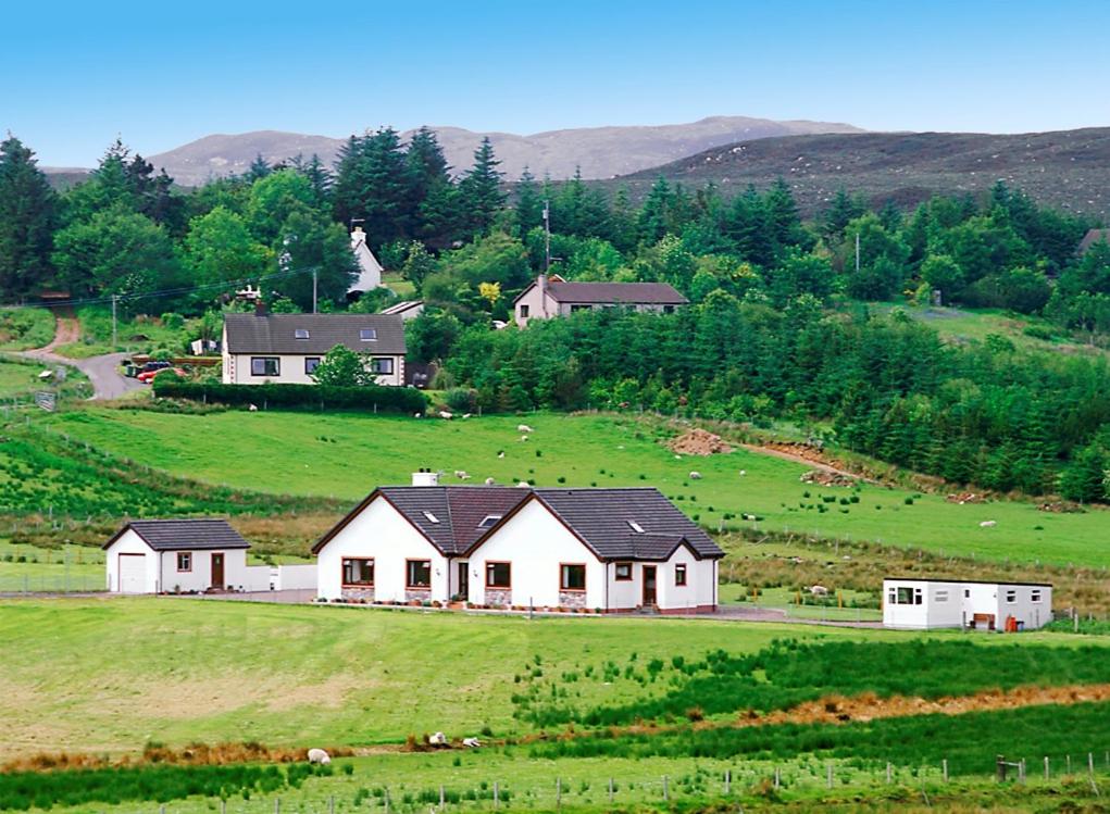 a large white house in a field with cows at The Sheiling in Laide