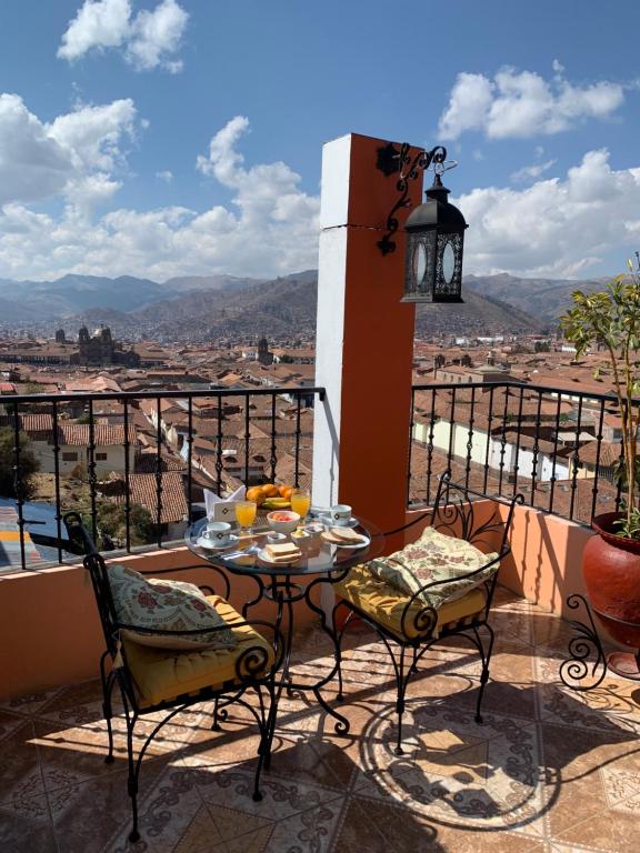 a table and chairs on a balcony with a view at Hostal Qolqampata in Cusco