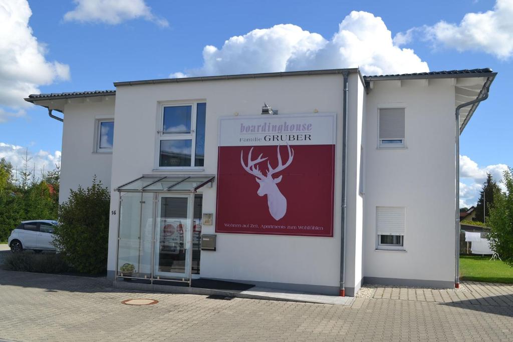 a white building with a deer sign on it at Boardinghouse Gruber in Kranzberg