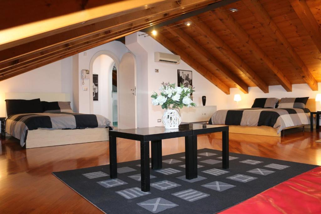 Una habitación con dos camas y un jarrón de flores sobre una mesa. en Accogliente appartamento moderno, vicino a Venezia, en Mestre