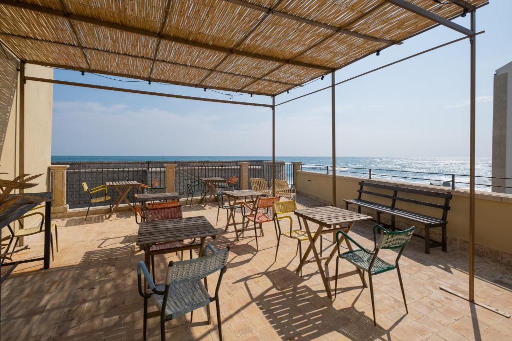 un patio con tavoli, sedie e vista sull'oceano di Hotel Gutkowski a Siracusa