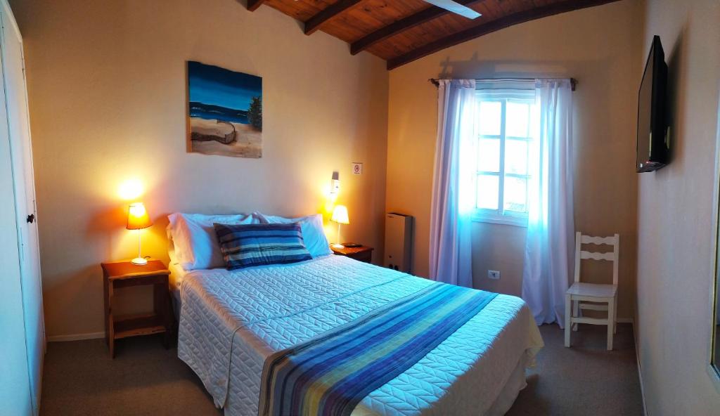 un dormitorio con una cama grande y una ventana en la Hostería Costa Bonita en Villa Gesell