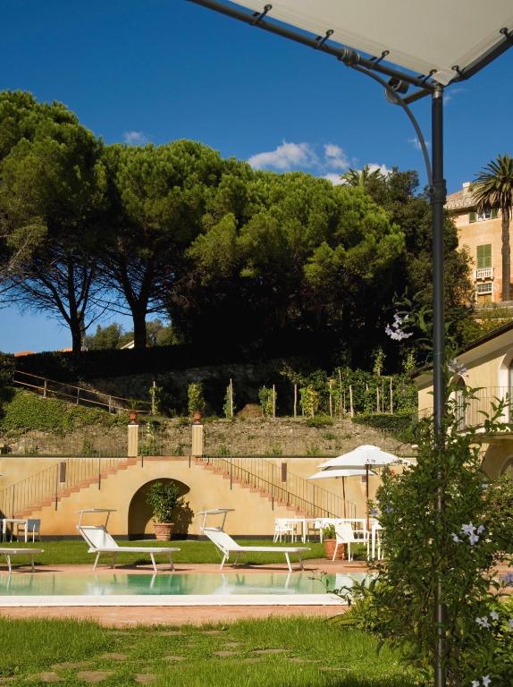 a pool with chairs and tables and an umbrella at Villa Agnese in Sestri Levante