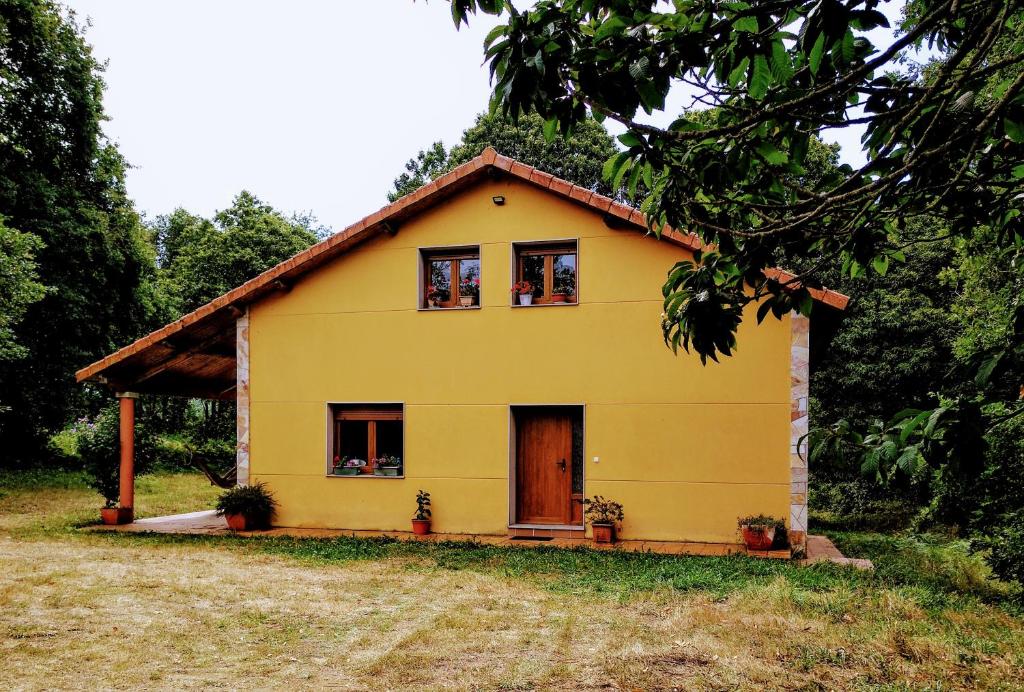 uma casa amarela com duas janelas e uma porta em CASA DE CIMADEVILA em Santiso