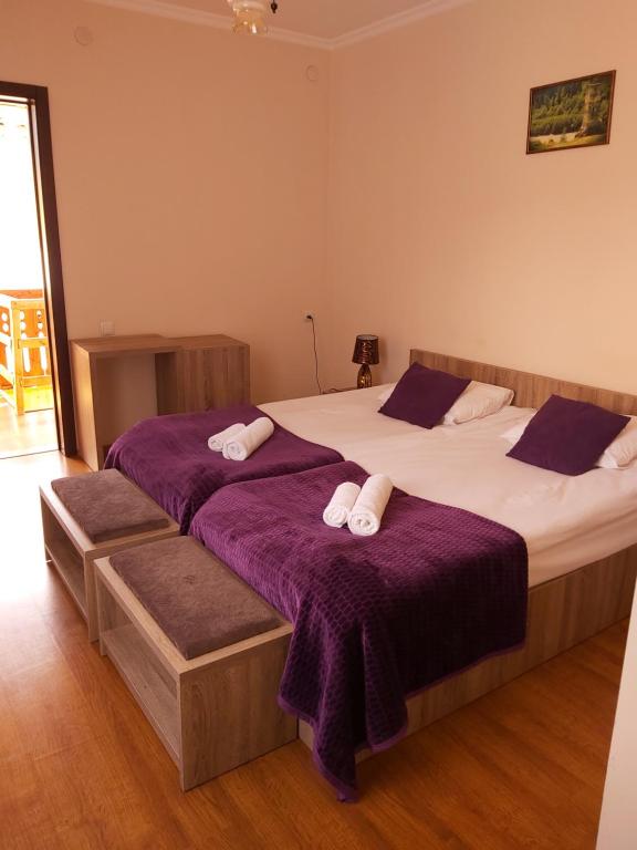two beds in a bedroom with purple sheets and towels at Svan House In Mestia in Mestia