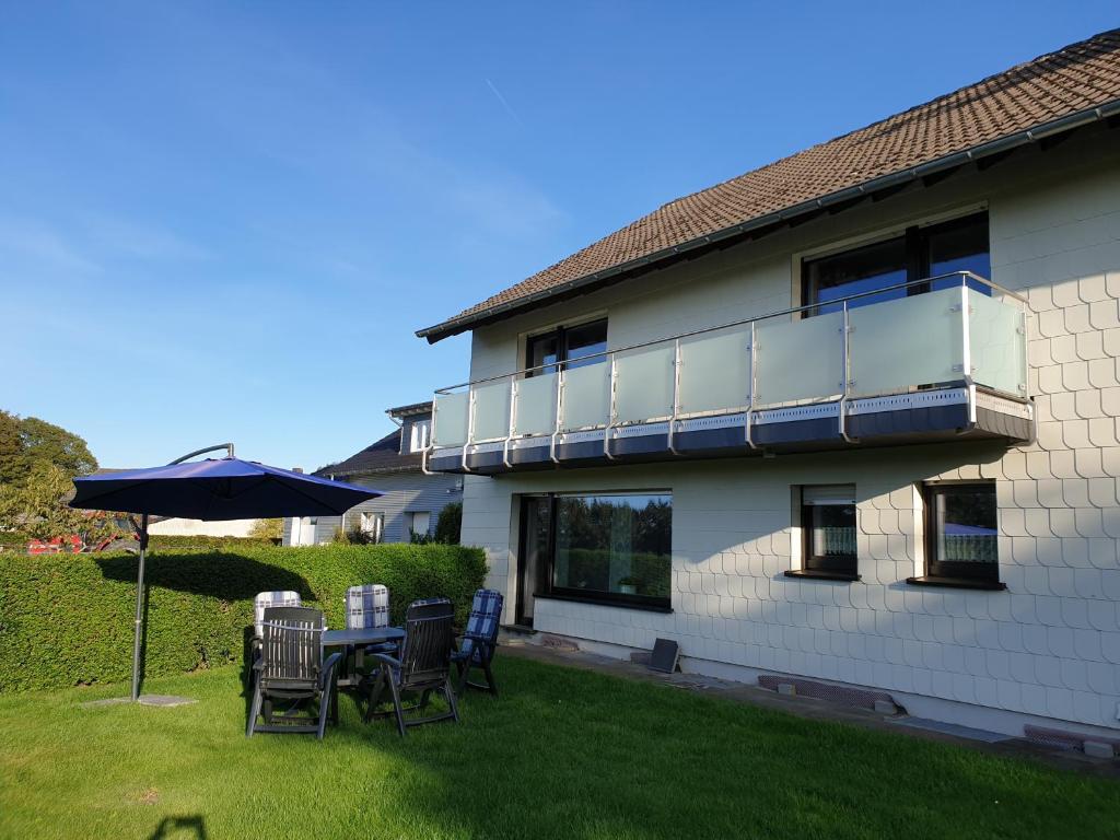 eine Terrasse mit Stühlen und einem Sonnenschirm vor einem Haus in der Unterkunft Ferienwohnung Heinen in Schleiden