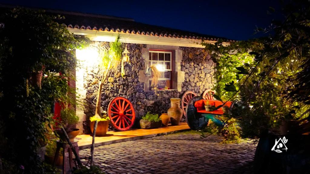uma casa de pedra com uma carroça vermelha no alpendre em Quinta do Paraíso em Porto Martins
