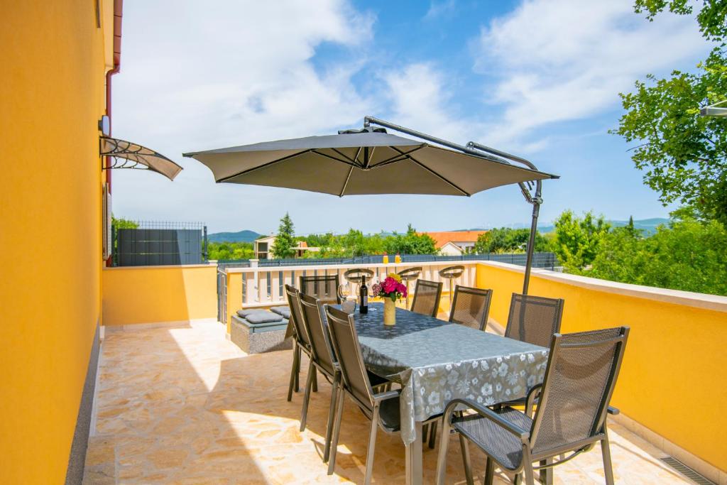 a patio with a table and chairs and an umbrella at Villa &quot;Mile&quot; in Katuni