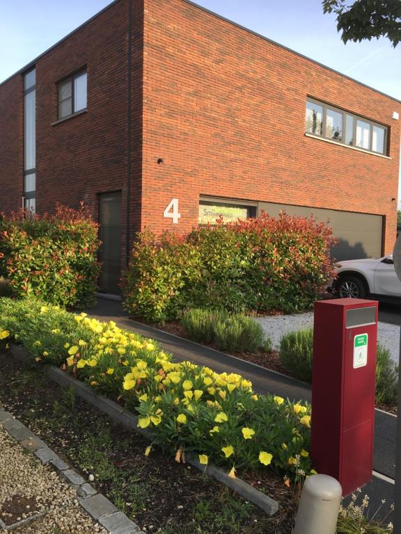 a brick building with a red mailbox in front of flowers at B&B Smile@life in Werchter