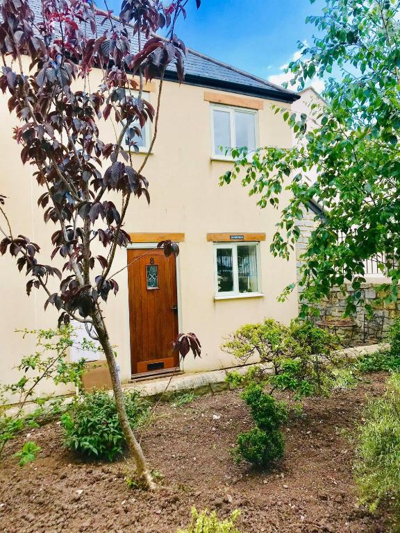 a house with a wooden door and a tree at Watchet Cottage in Watchet