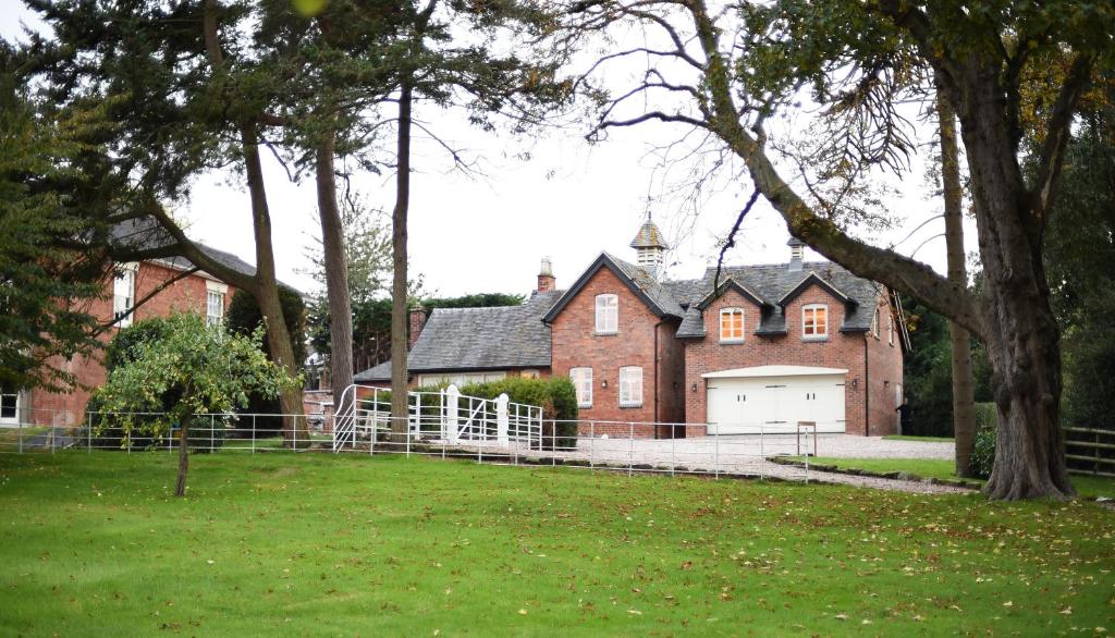a large red brick house with a white garage at Woodleighton Cottages in Uttoxeter