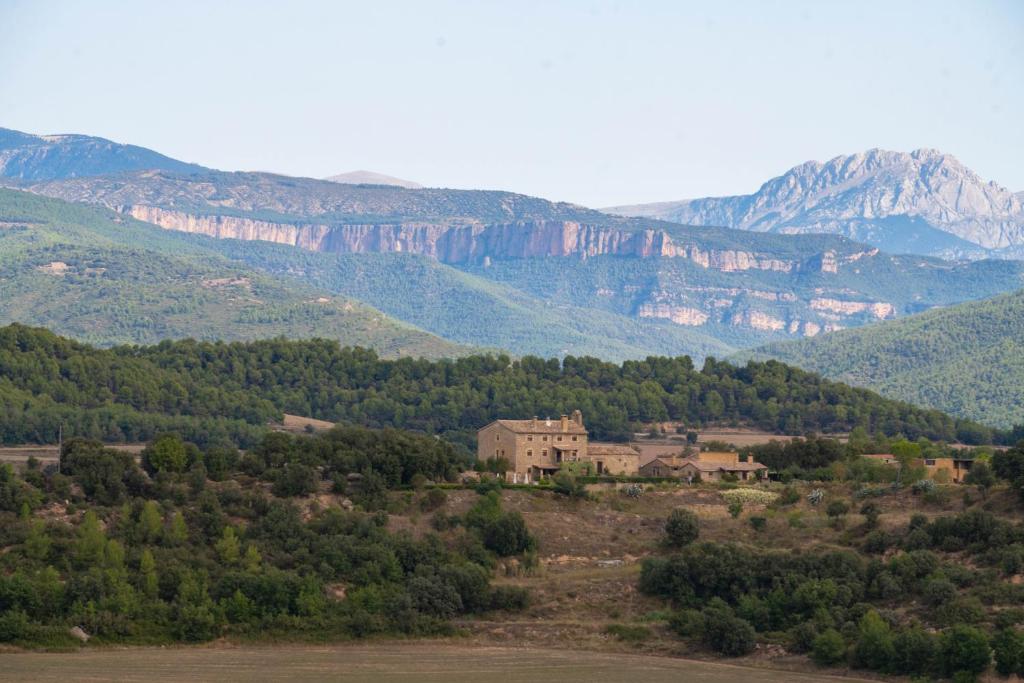 una casa en una colina con montañas en el fondo en Casa rural Sant Grau turismo saludable y responsable en Solsona