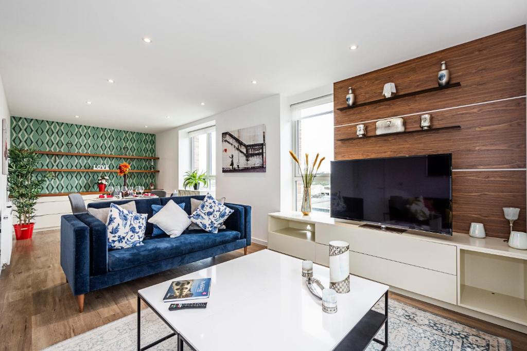 a living room with a blue couch and a tv at Chiswick Park Apartments London in London