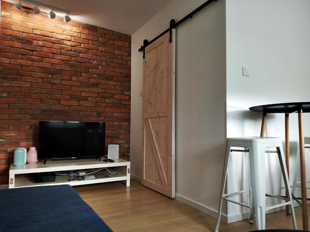 a living room with a television and a brick wall at CENTRAL PARK Apartment in Zielona Góra