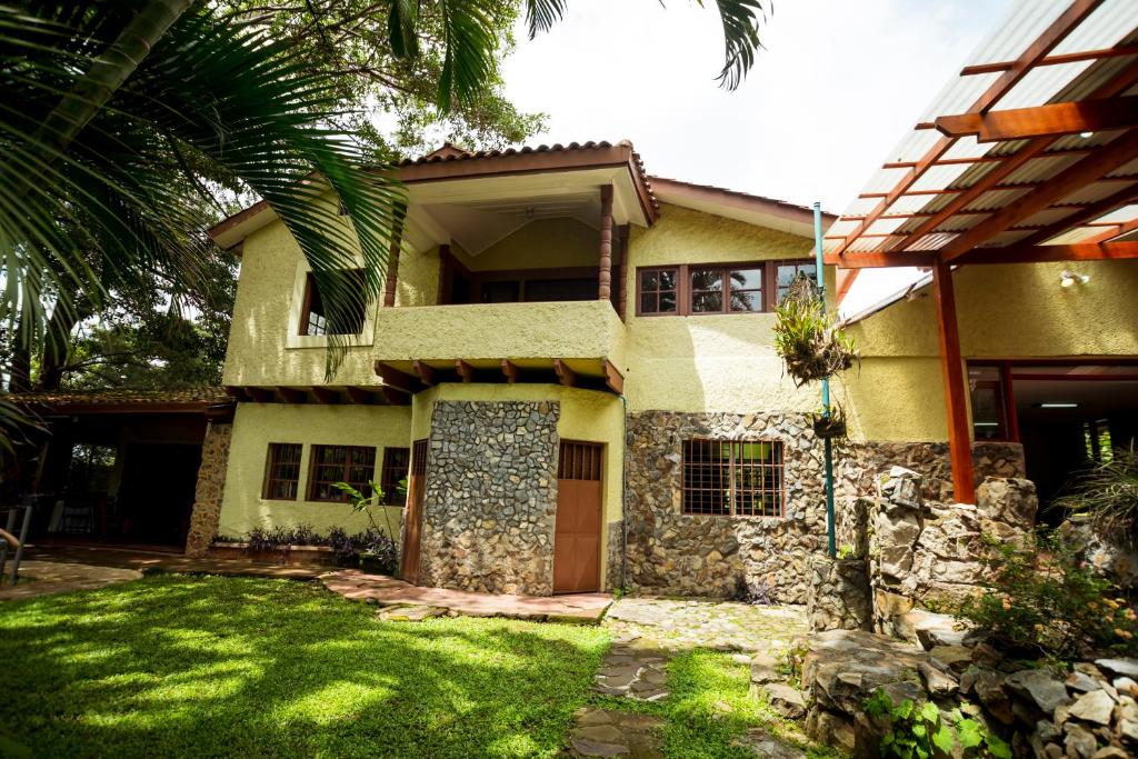 Casa de Piedra Escazú في سان خوسيه: منزل أمامه ساحة خضراء