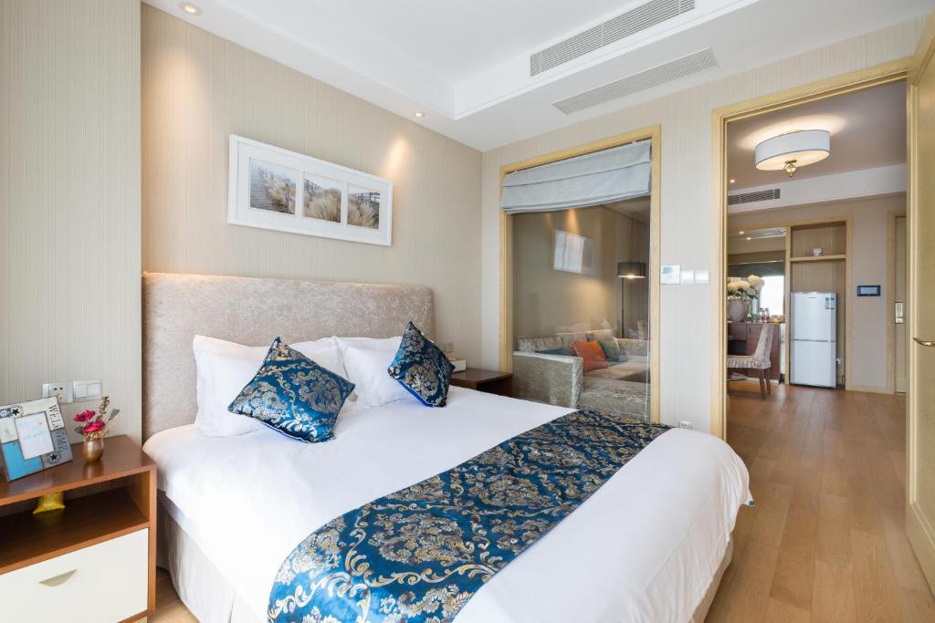 ein Schlafzimmer mit einem großen weißen Bett mit blauen Kissen in der Unterkunft Pinxiayuan Apartment in Lvcheng Resort in Zhoushan