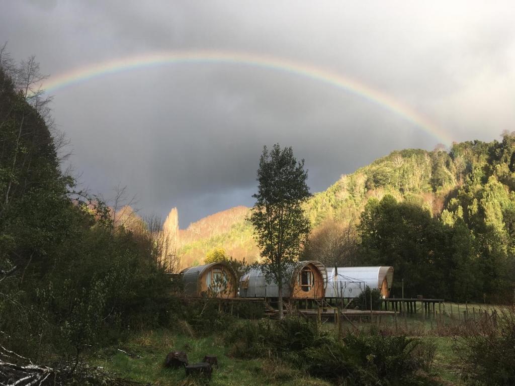 um arco-íris sobre uma velha estação de comboios com um comboio em Refugios Canto del Agua em Villarrica