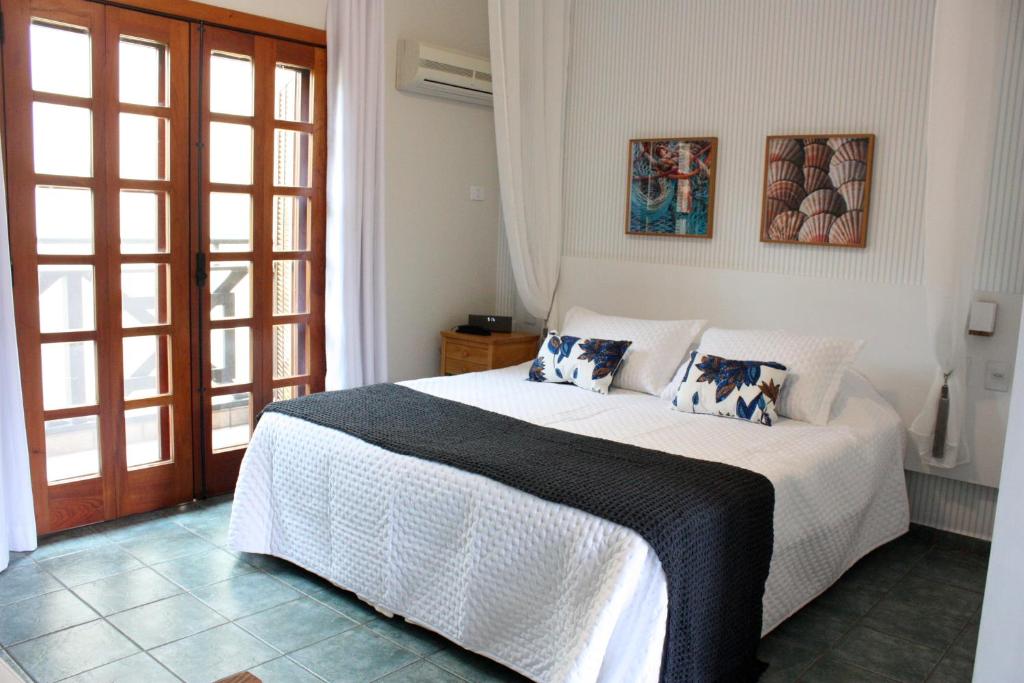 Un dormitorio con una cama blanca con almohadas. en Suite Ilhaflat en Ilhabela