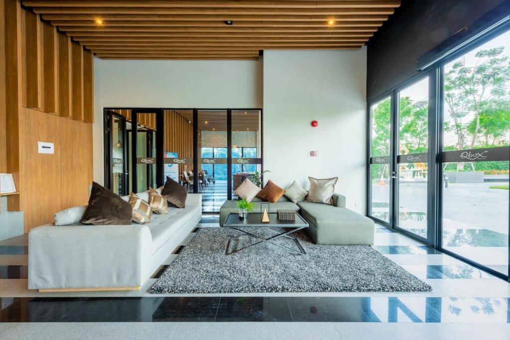 A modern lobby seating area arranged around a central coffee table beside tall windows.