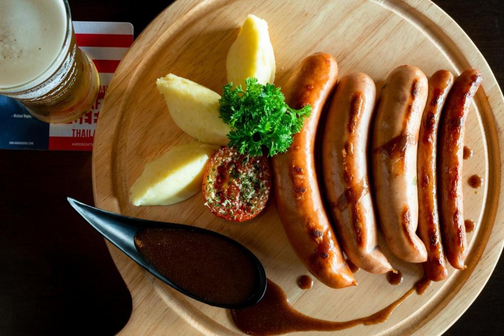 A plated meal of grilled sausages, apple wedges and sauce.