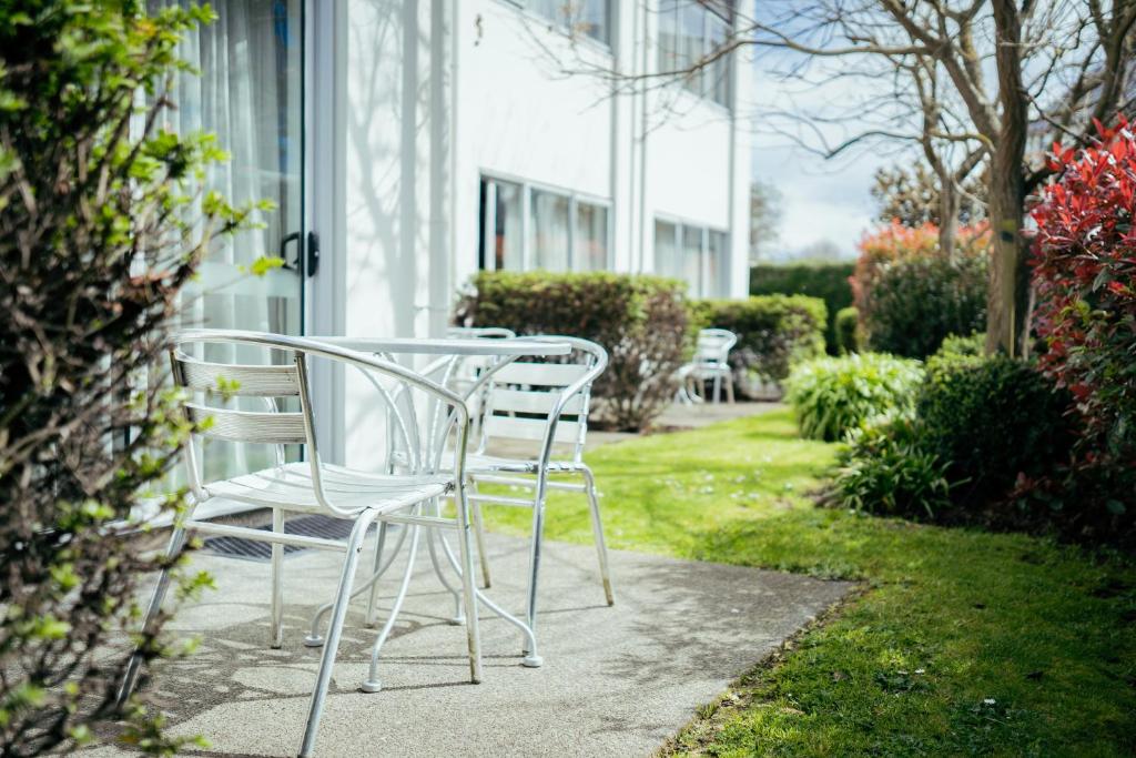 una mesa y sillas sentadas fuera de un edificio en Airport Delta Motel en Christchurch